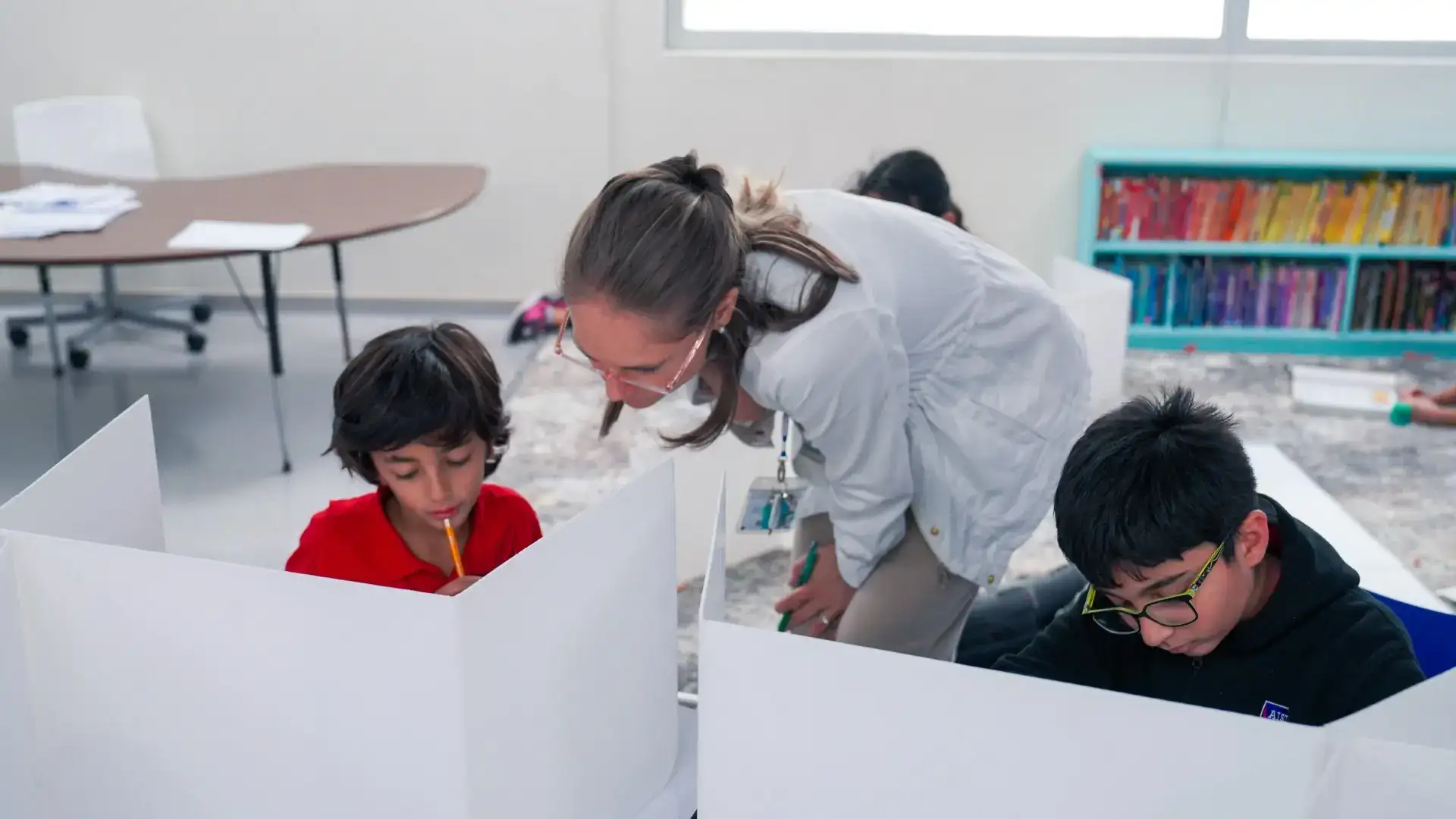 An AISJ teacher leaning in to help students working at their desks