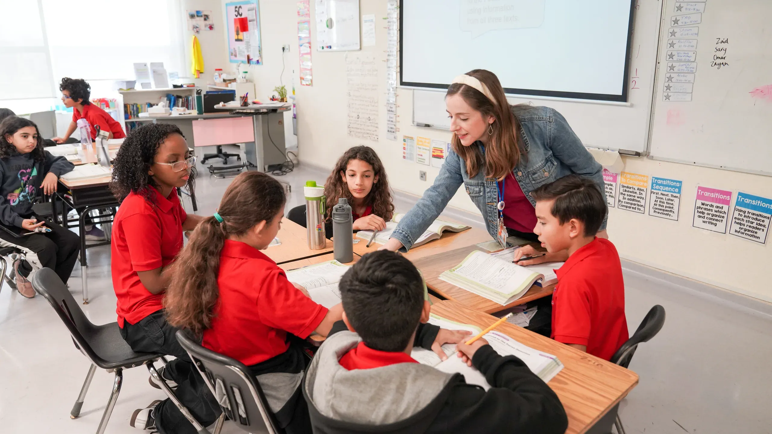 An AISJ elementary teacher guiding a small student group mid-lesson