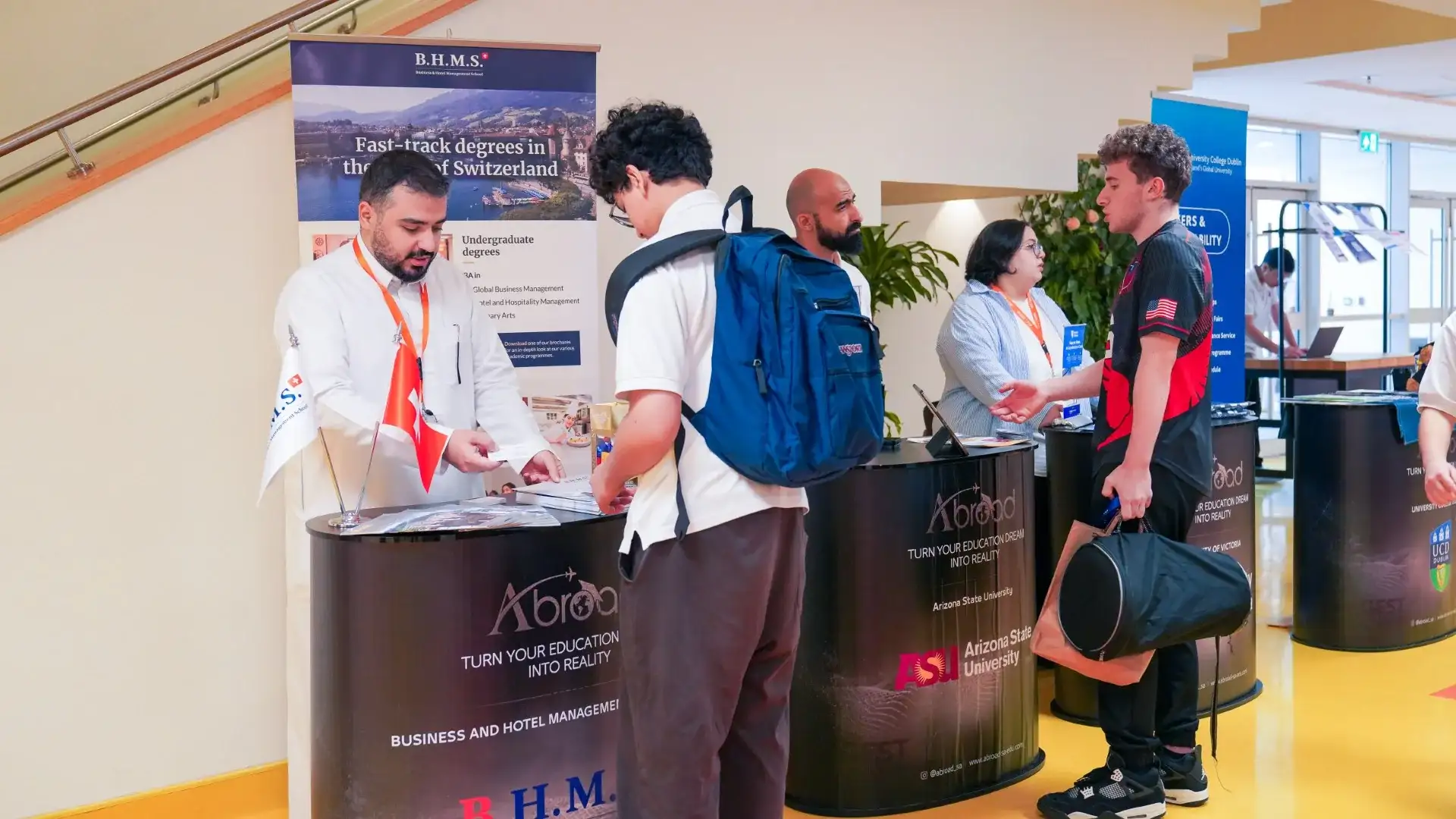 A high school student talks with a university representative at a booth during AISJ's college fair.