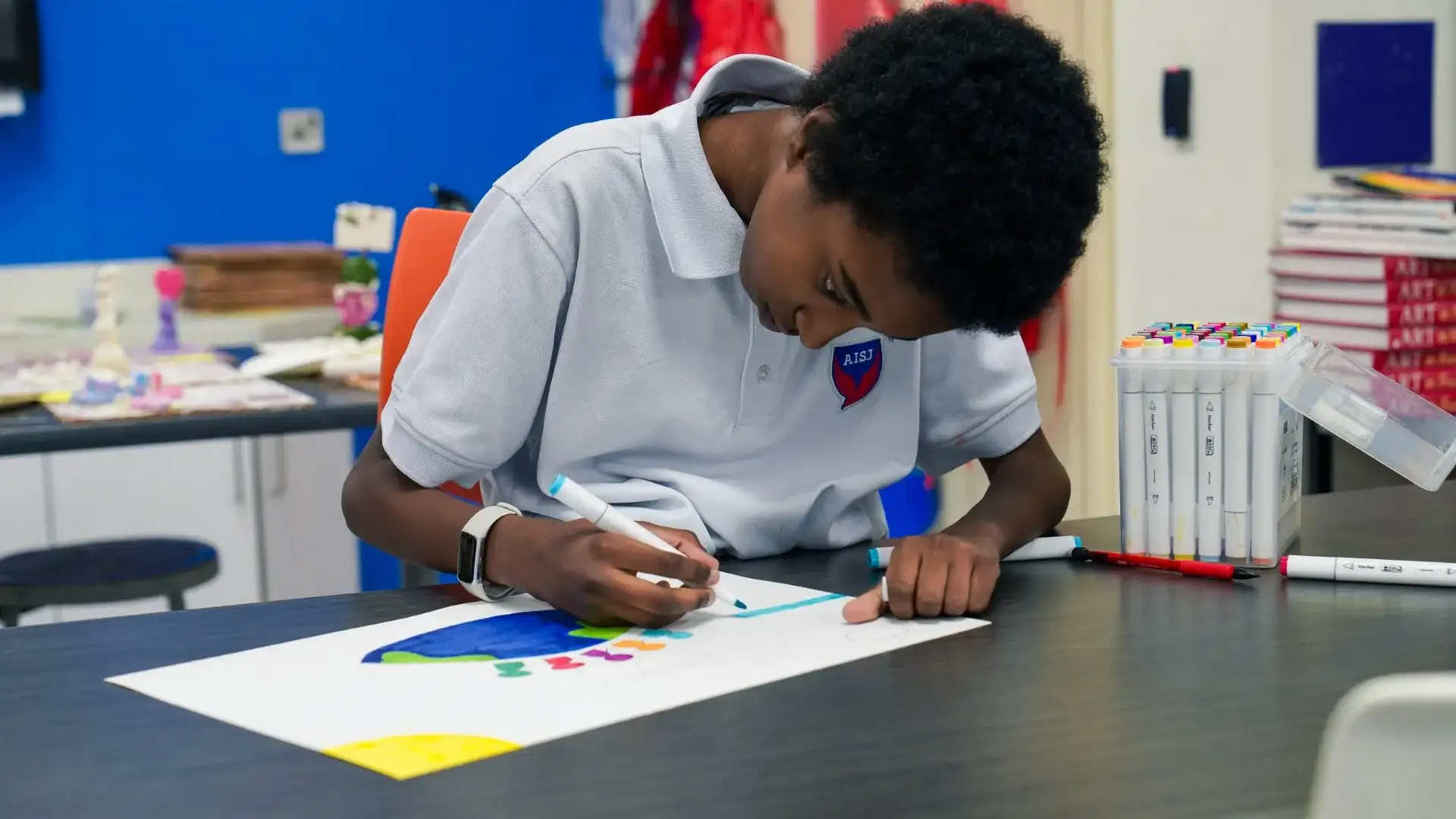 An AISJ High School student drawing and writing at a studio table