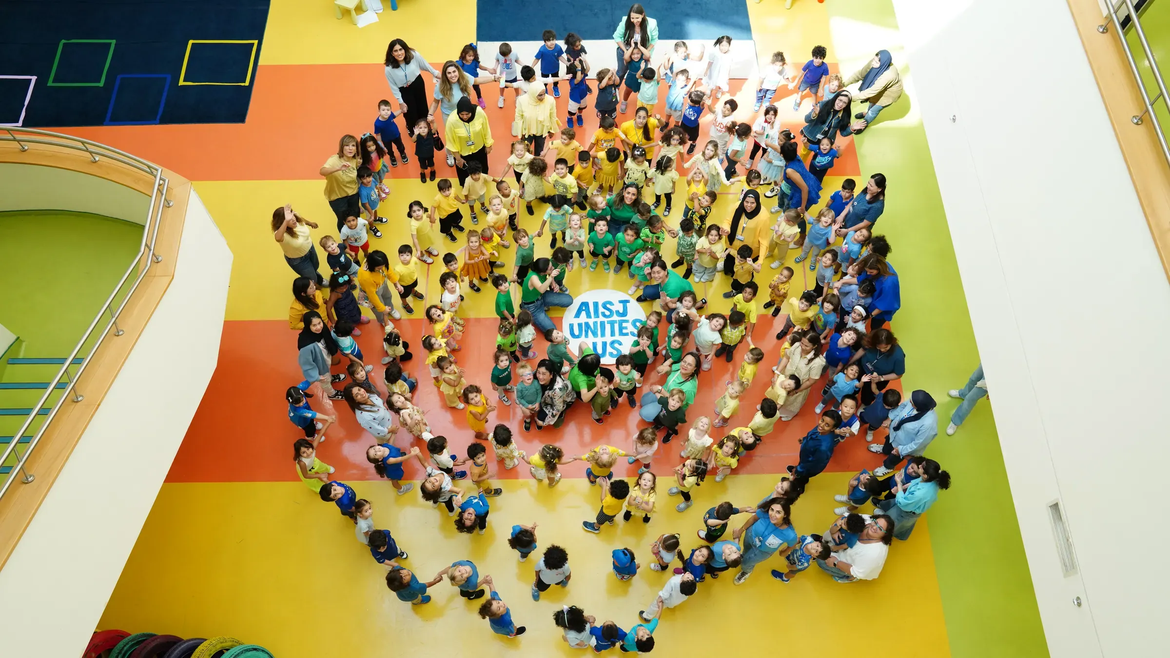 Students forming a heart around an 'AISJ Unites Us' sign
