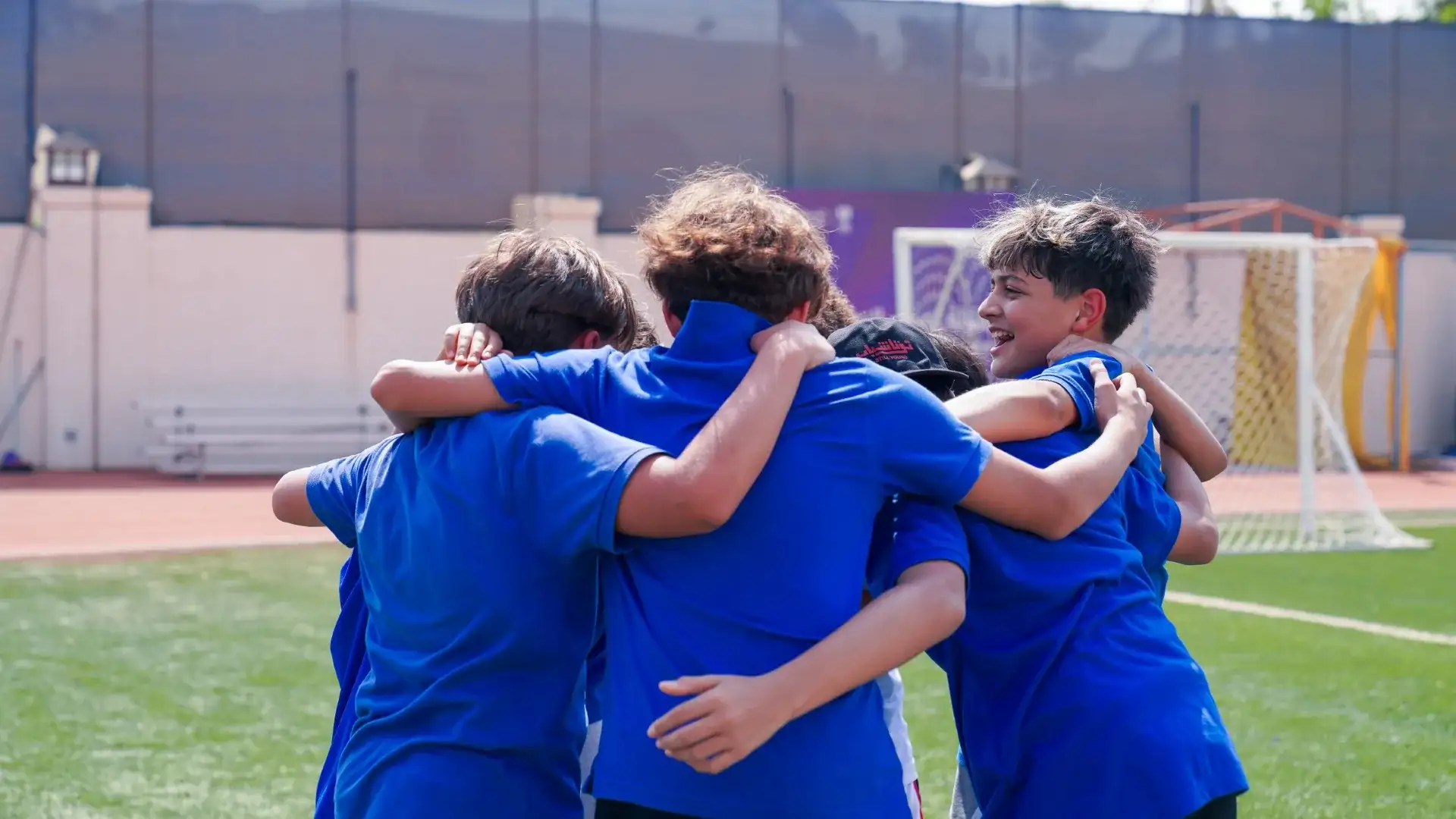 AISJ student-athletes in a team huddle on the sports field