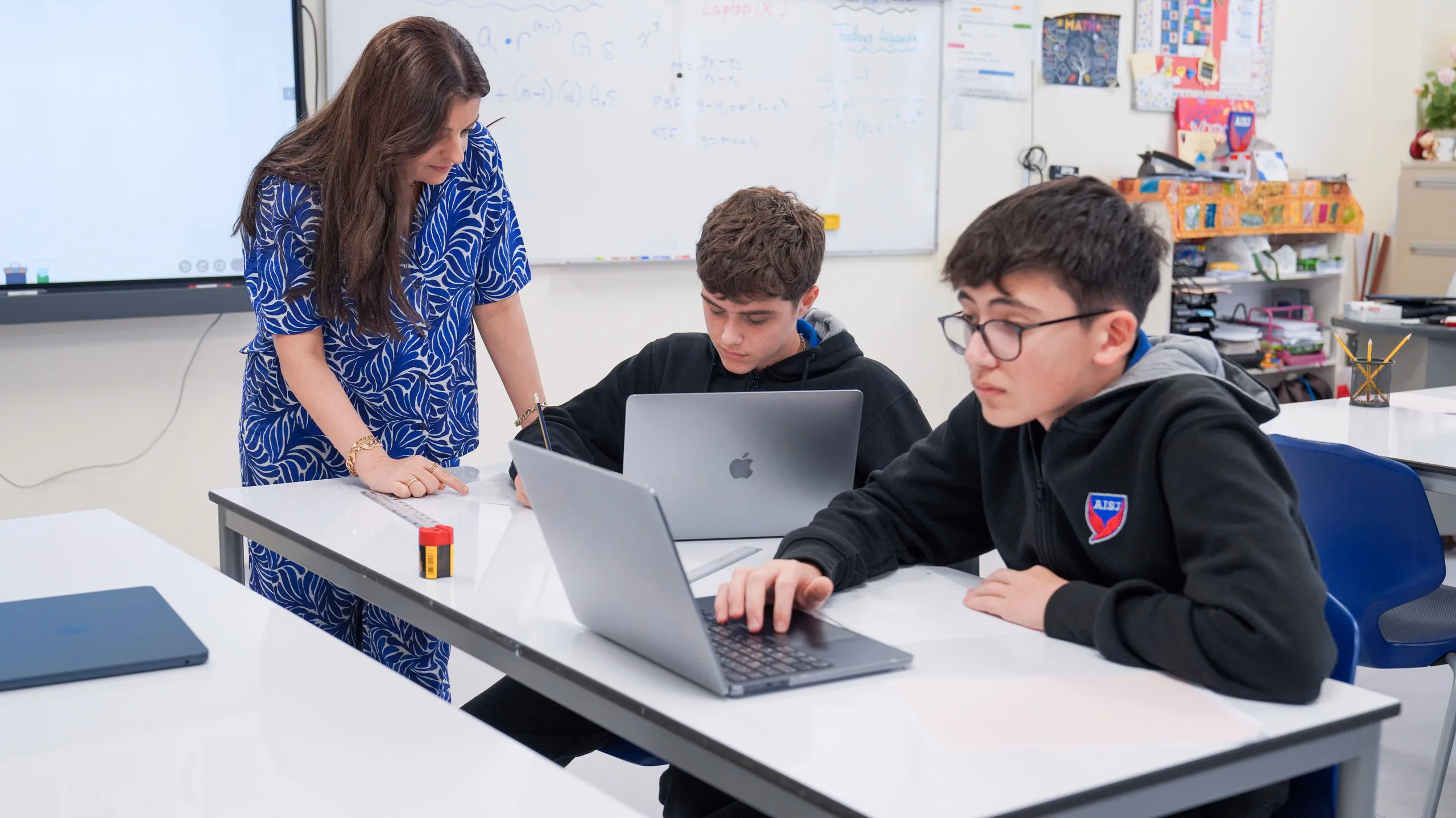 AISJ Middle School students working on laptops with teacher guidance