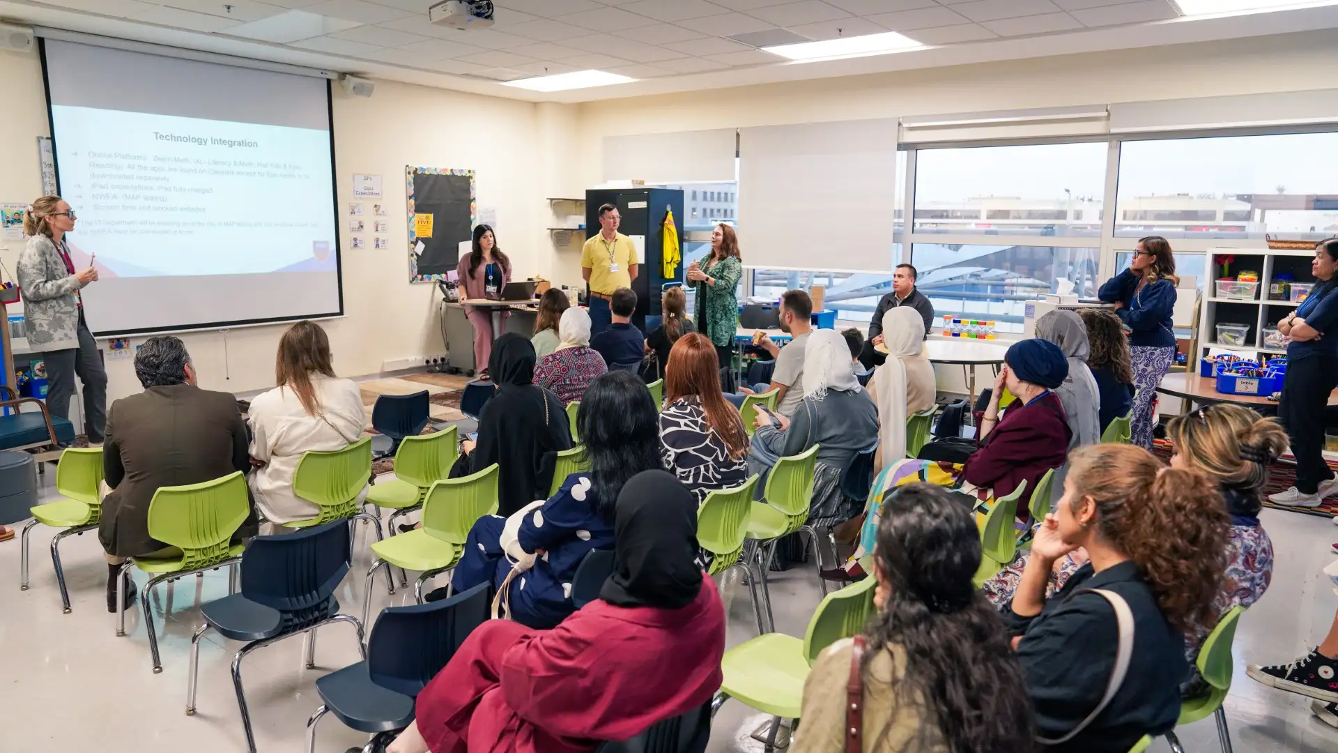 AISJ parents seated at tables during a presentation in a school learning space